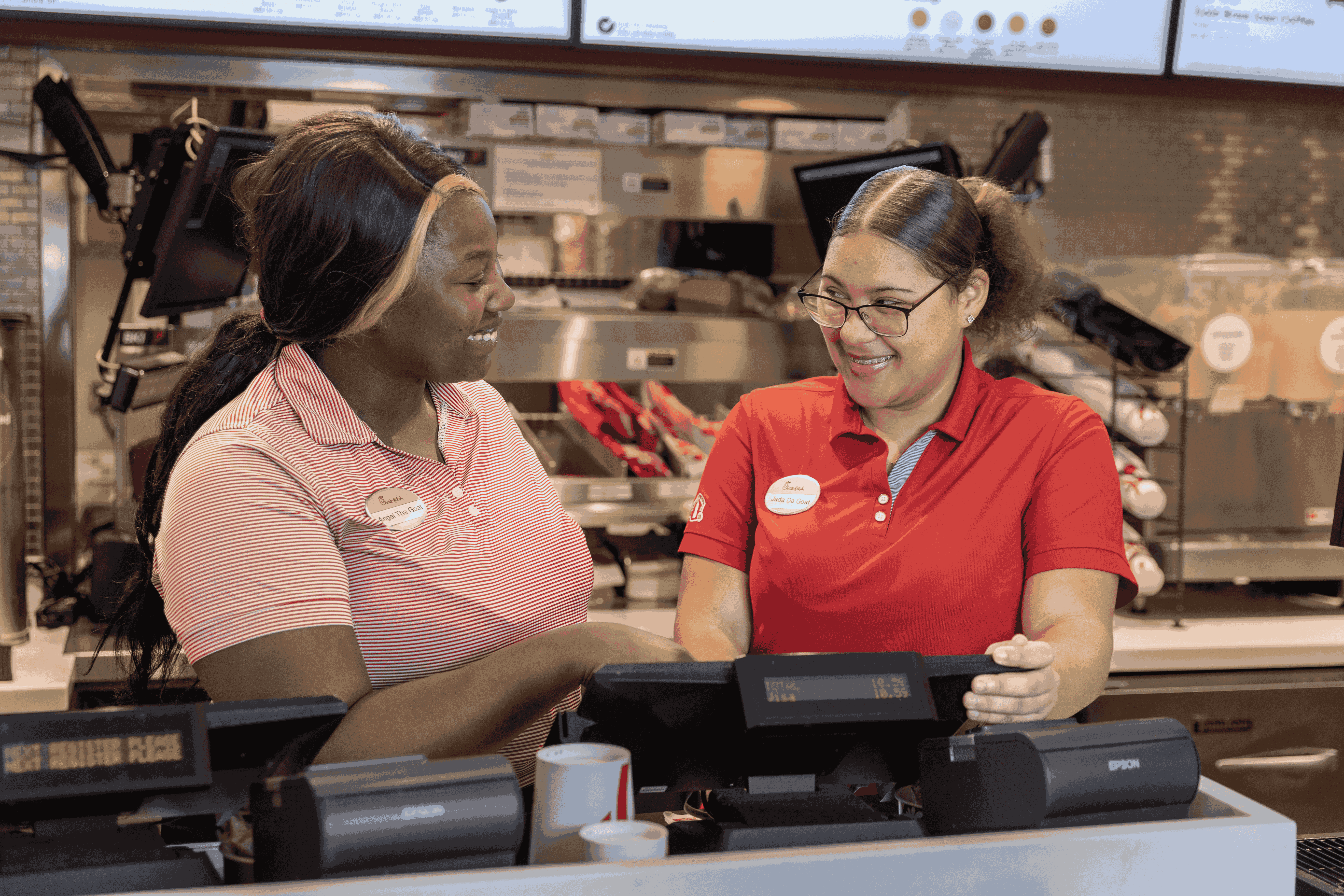 Two airport cashiers smiling at each other