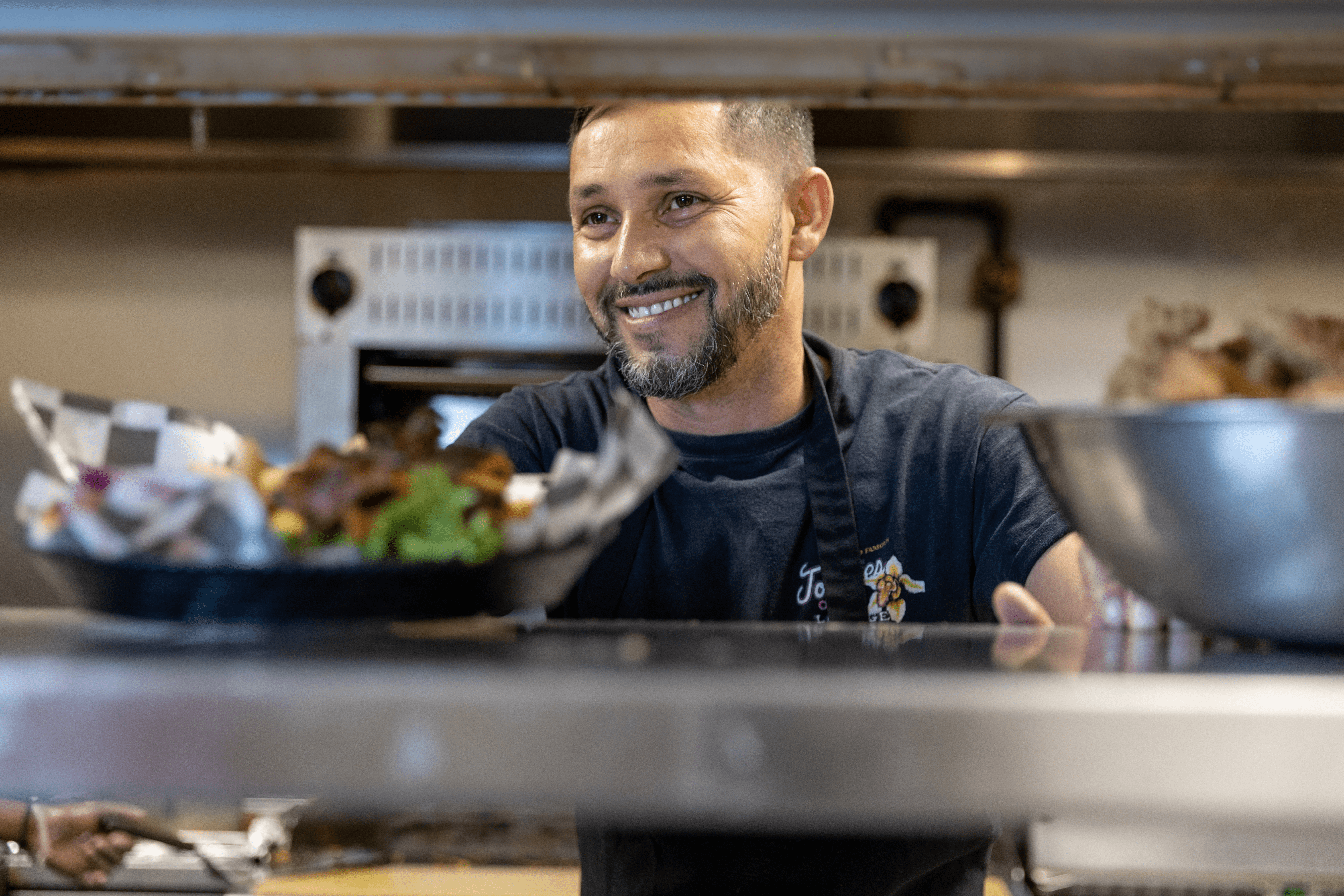 Prep cook smiling to team member behind kitchen pass