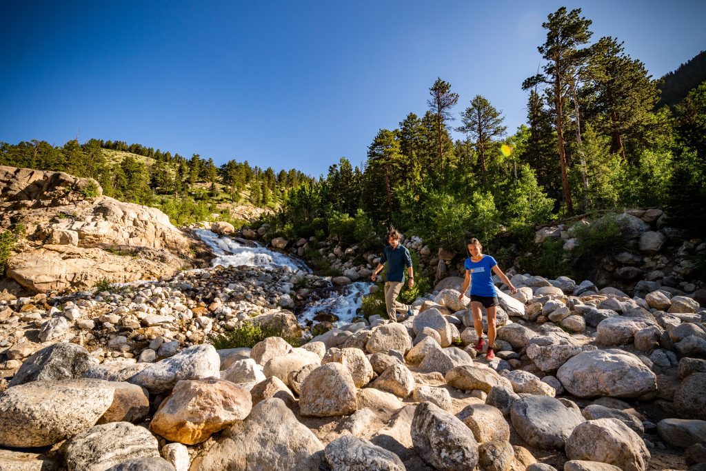 Two hikers walking in front of a stream