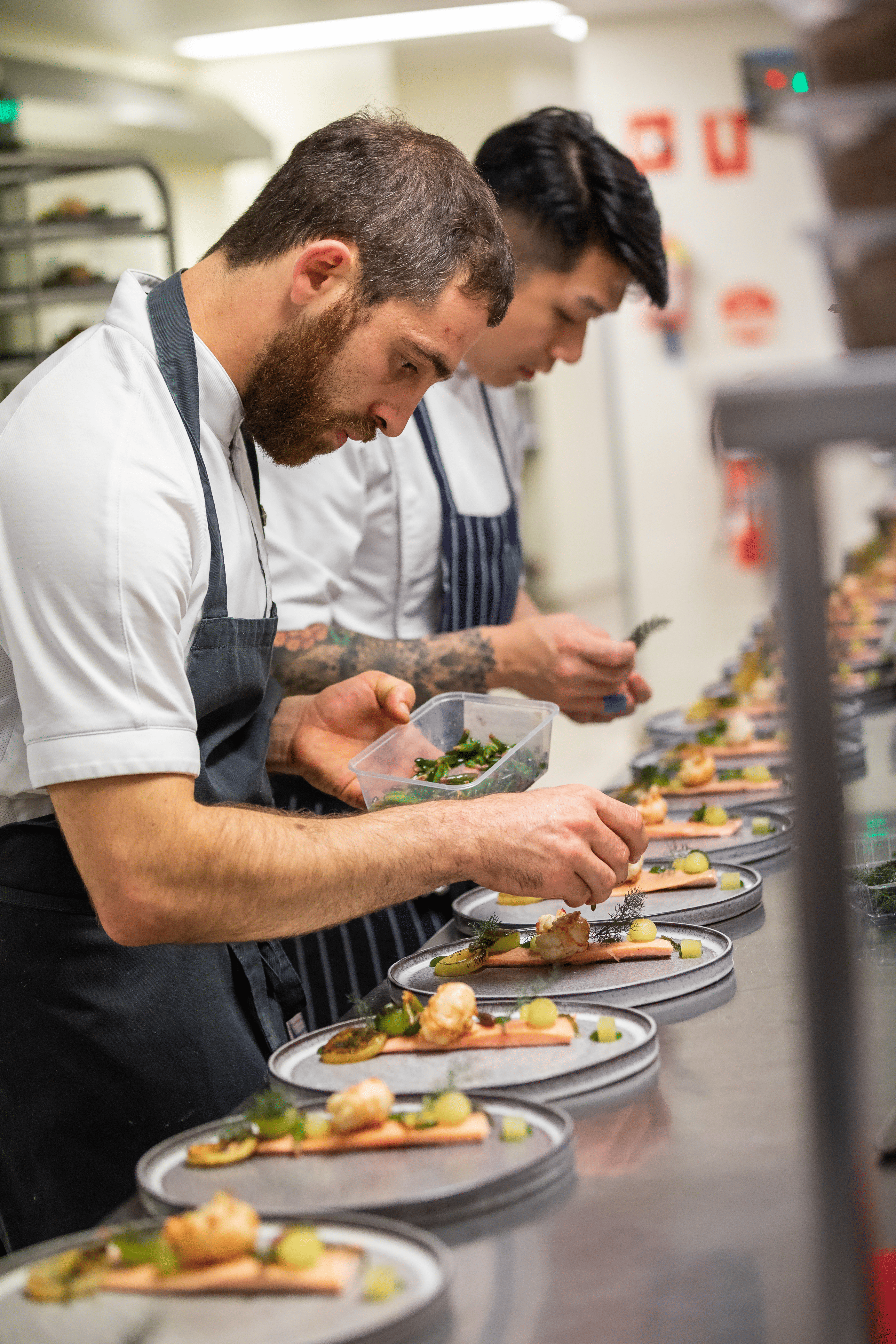 Two chefs prepping food plates back of house